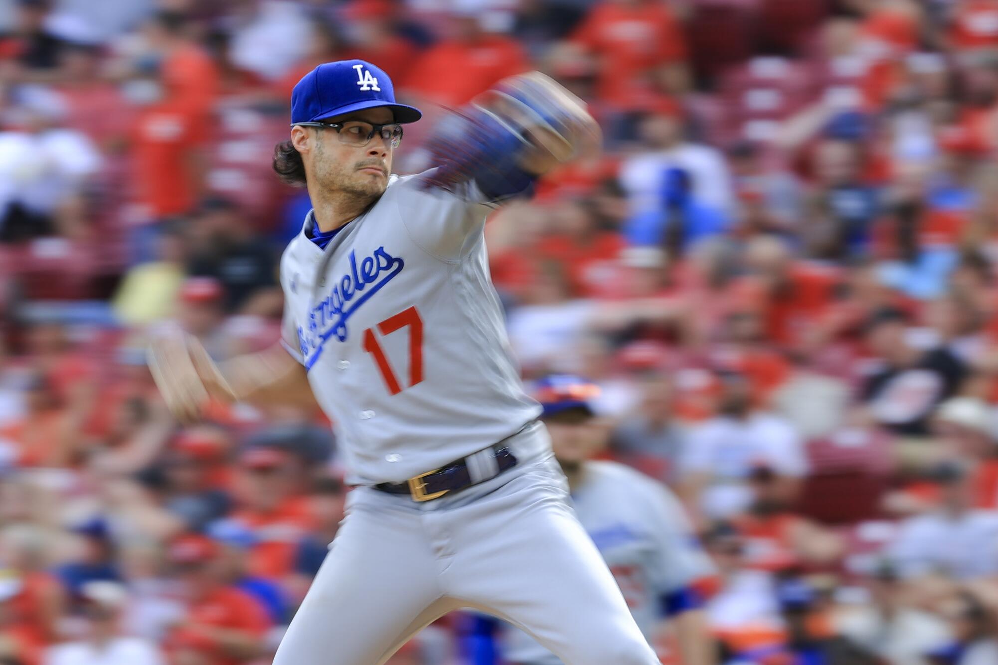 A man in a Dodgers uniform pitches a baseball.