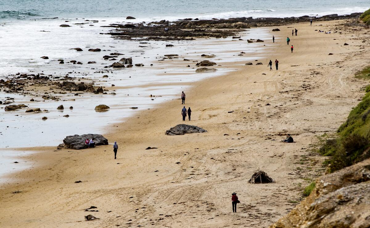 People walk along the shore at Crystal Cove State Beach.