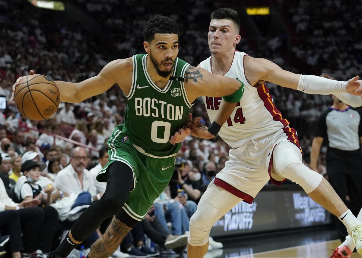 Boston Celtics forward Jayson Tatum dribbles the ball as Miami Heat guard Tyler Herro defends.