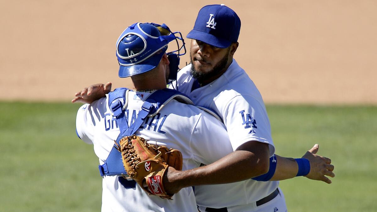 Dodgers closer Kenley Jansen is congratulated by catcher Yasmani Grandal after a 2-1 victory over the Cincinnati Reds on Sunday afternoon at Dodger Stadium.