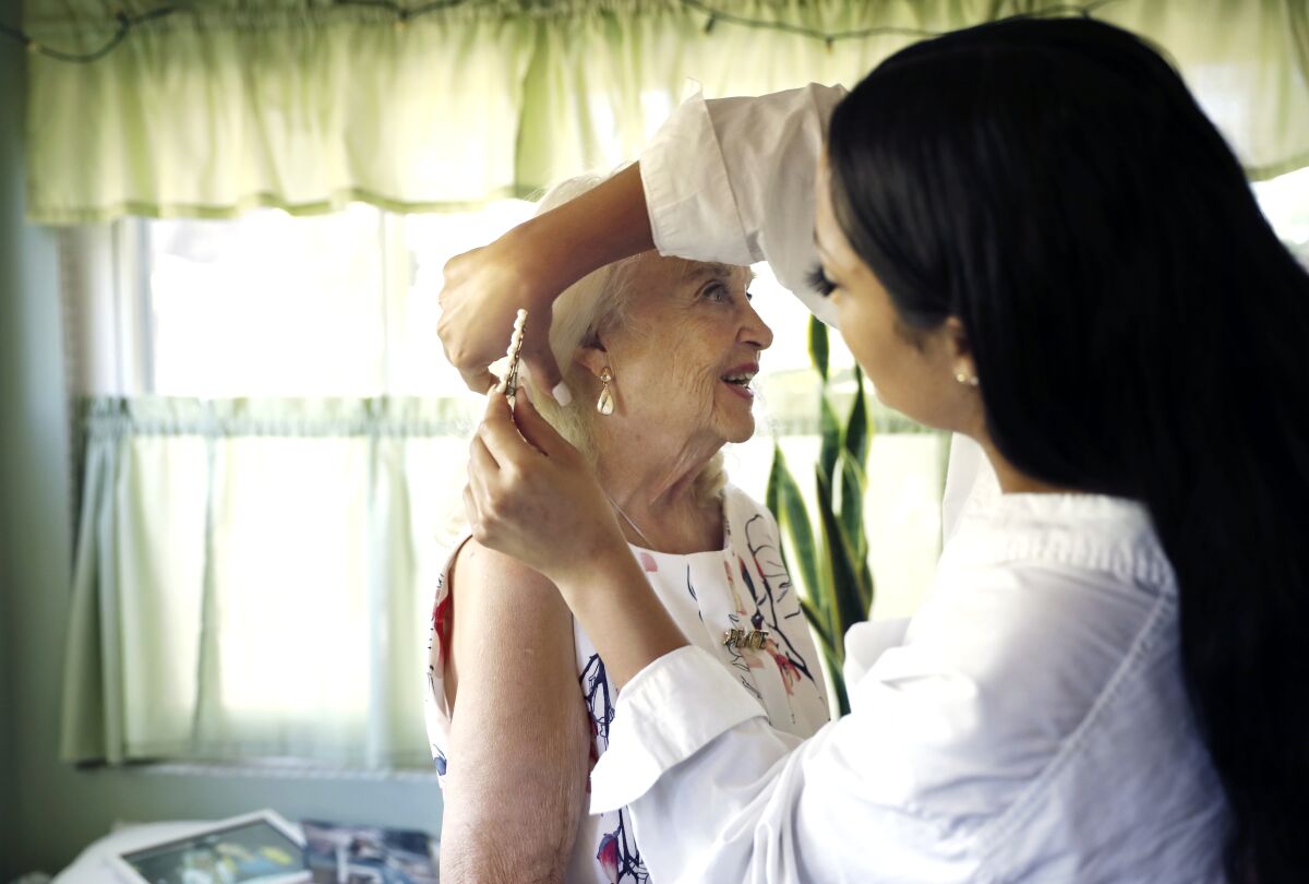 Reita Green, left, gets help with her hair by friend and wallpaper partner Beverly Pate at Green's Burbank home.