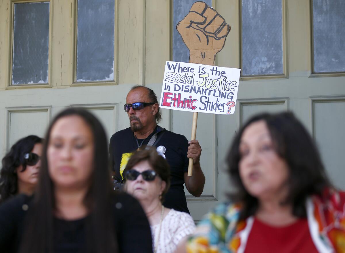 A man at a rally holds a sign that says, "Where is the social justice in dismantling ethnic studies?"