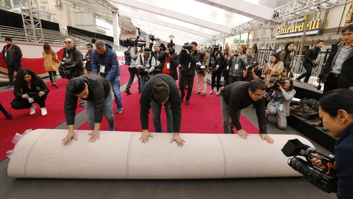 Estuardo Marrorquin (from left), Sergio Marroquin and Rudy Morales roll out part of the red carpet on Hollywood Boulevard in front of the Dolby Theatre as preparations continue for the 91st Oscars.