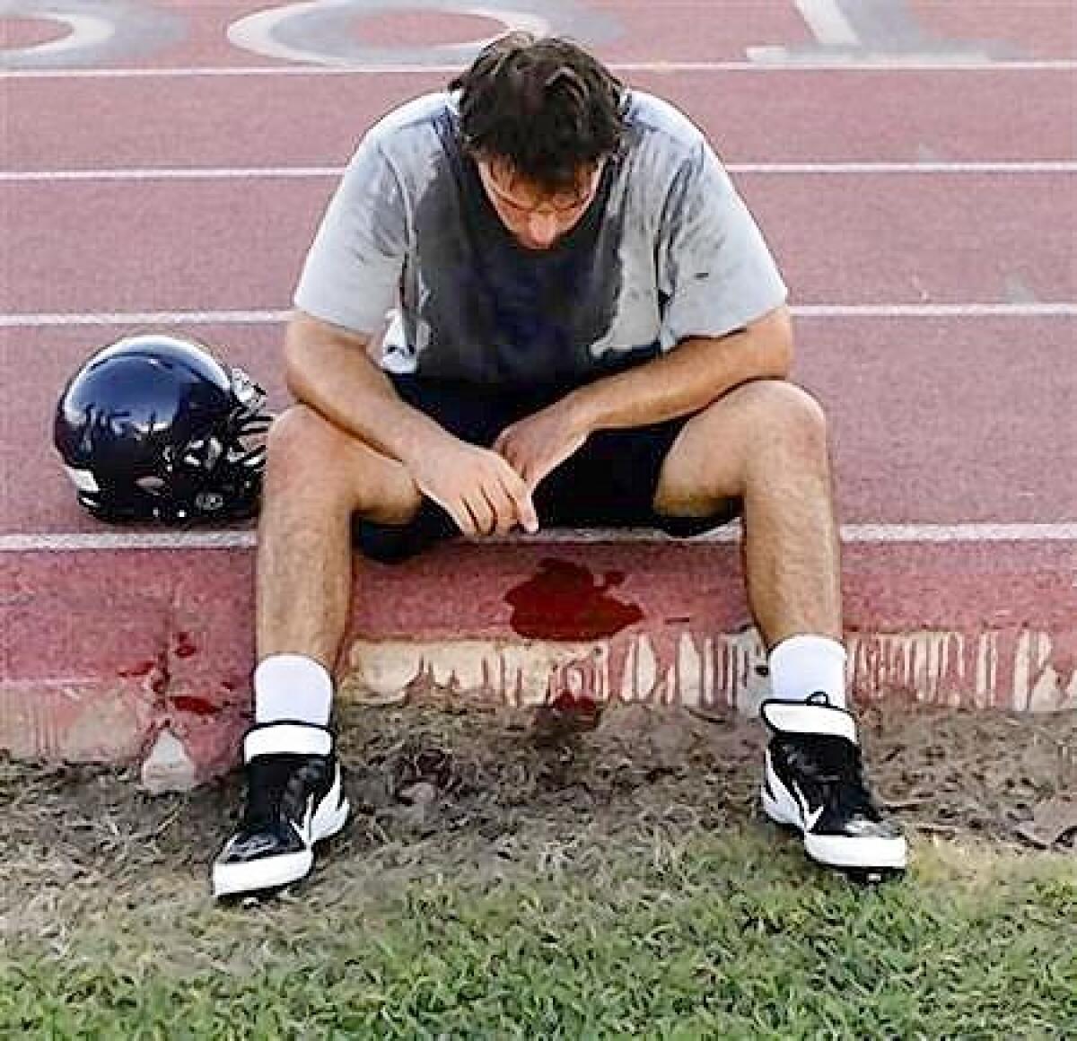 McClintock High School Chargers football player Joe Sanford takes a break from practice after feeling light-headed in Tempe, Arizona