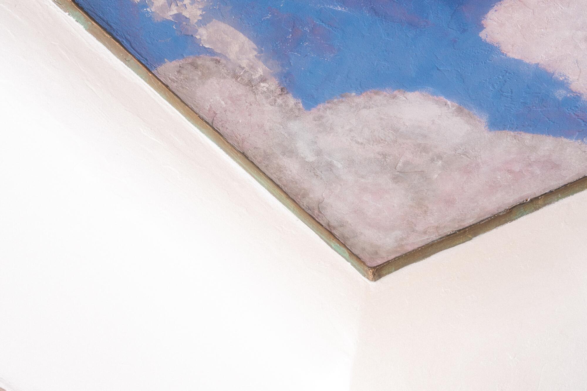 A picture of the corner of a ceiling painted with a blue sky and clouds.
