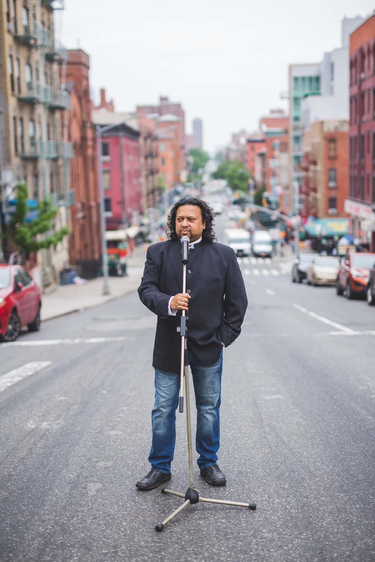 Comedian-playwright Alaudin Ullah stands on a city street.