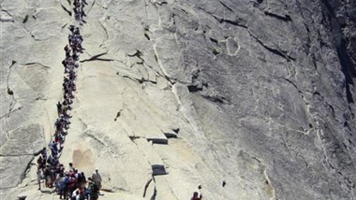 DANGER ON THE DOME / Overcrowding: Hikers swarming Yosemite's Half Dome  create a bottleneck at the treacherously steep granite climb to the summit
