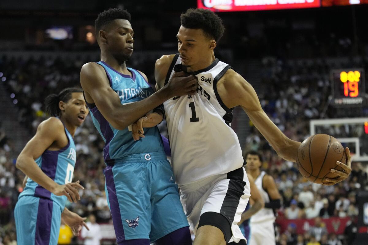 Spurs center Victor Wembanyama, right, drives against Hornets forward Brandon Miller in his NBA debut Friday.