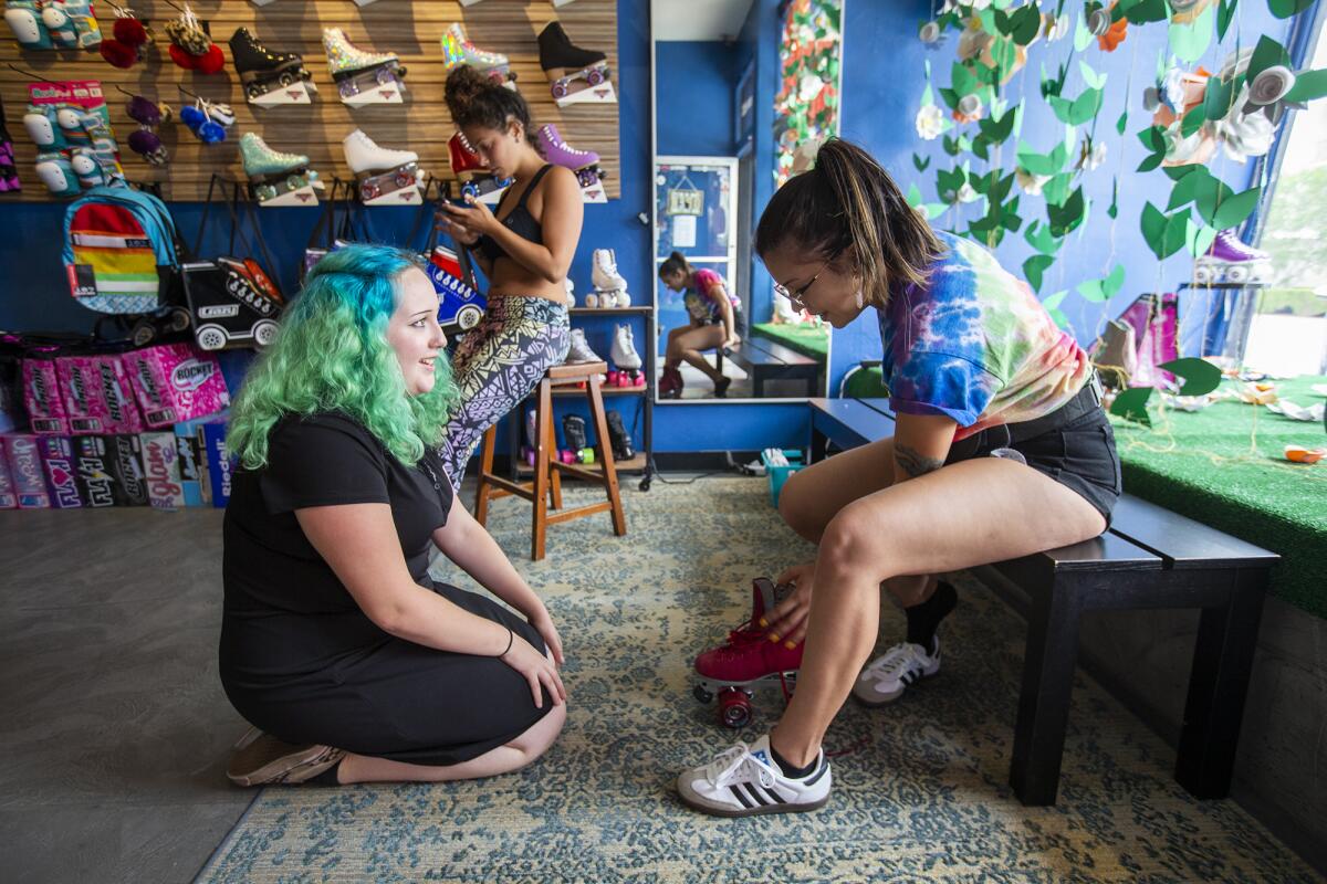 Katie Charlton, left, with Surf City Skates, works on fitting a pair of roller skates on Jennifer Varela, 24, from San Diego, in Huntington Beach on Tuesday.