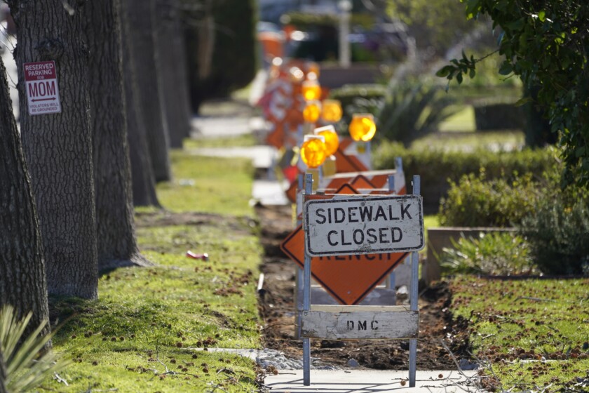 A sidewalk is closed as crews work on repairs in Upland, Calif., on Monday, Jan. 24, 2022. After estimating a loss in revenue in the early months of the pandemic in 2020, city officials say Upland is now doing well financially, boosted partly by federal pandemic aid. The city plans to use part of that aid to repave parking lots and repair hundreds of sections of sidewalks. (AP Photo/Damian Dovarganes)