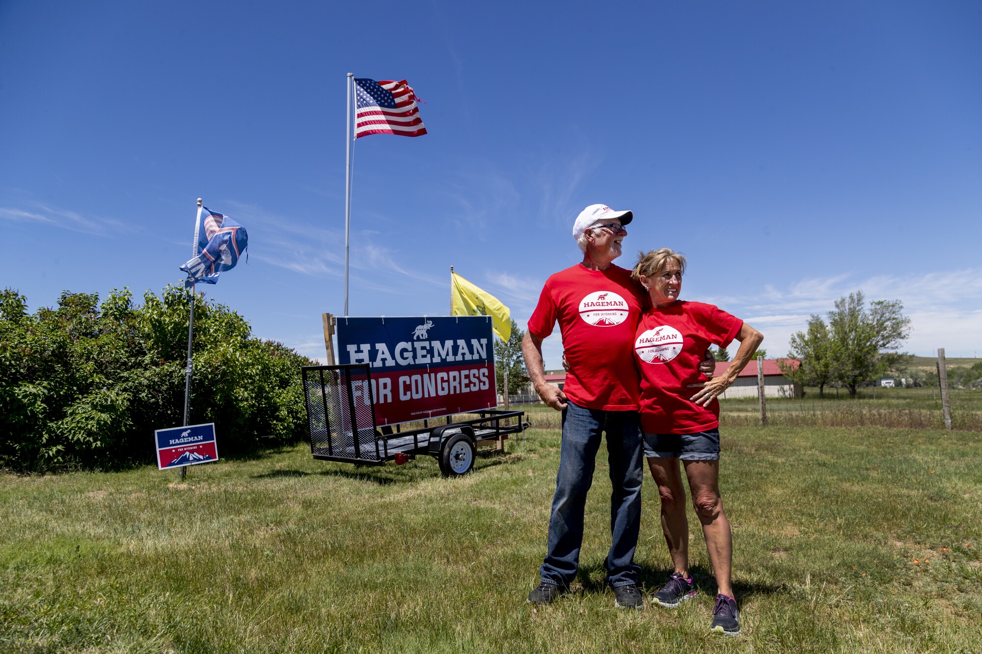 A man and woman in red shirts stand by a "Hageman for Congress" sign
