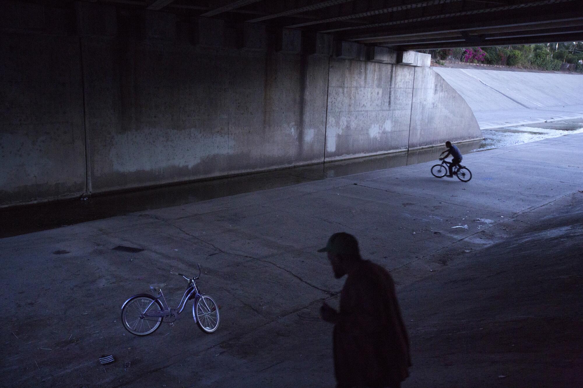 Ron Clark rides his bike to his friend Eric's place under a bridge along the L.A. River in May 2018.