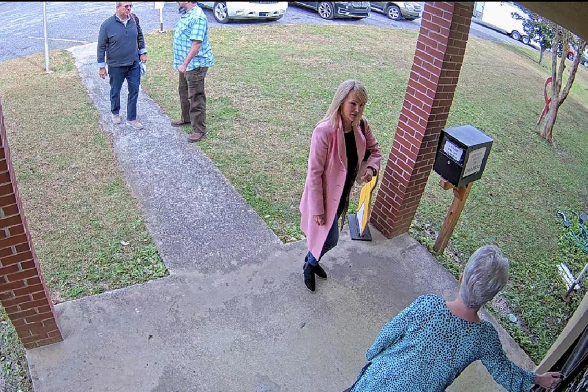 In this Jan. 19, 2021 image taken from Coffee County, Ga., security video, Cathy Latham, bottom, who was the chair of the Coffee County Republican Party at the time, greets a team of computer experts from data solutions company SullivanStrickler at the county elections office in Douglas, Ga. Records show that the team traveled to the rural south Georgia county to copy software and data from elections equipment. The Georgia secretary of state's office has said the visit was an "alleged unauthorized access" of election equipment. (Coffee County via AP)