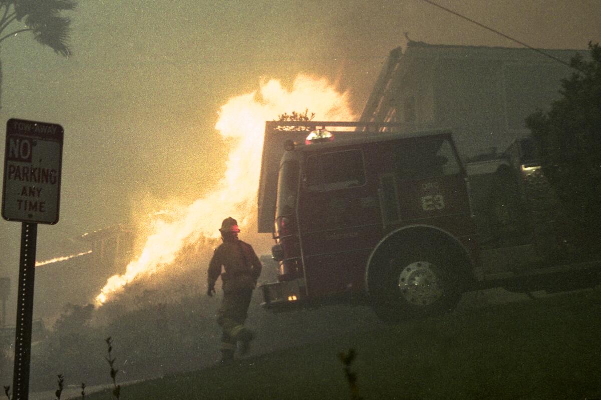 Flames advance down the hill from Mystic Hills as a firefighter searches for a hydrant in the Laguna Beach wildfire of 1993.