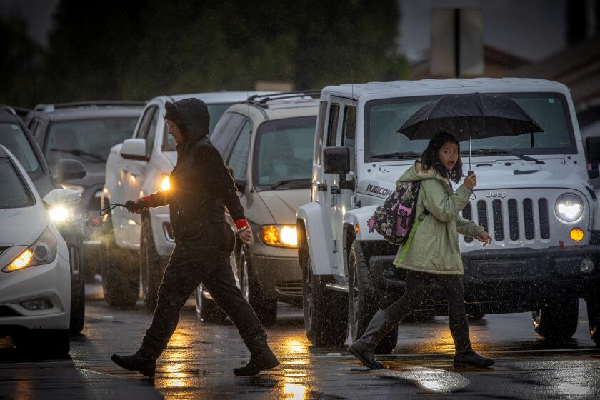 LA VERNE, CA - FEBRUARY 20: Parents take their children to school in La Verne Tuesday morning, February 20, 2024, as steady rain falls across much of Los Angeles County. Baseline La Verne, CA. (Irfan Khan / Los Angeles Times)