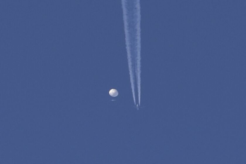 En esta foto proporcionada por Brian Branch, un gran globo se desplaza por encima de la zona de Kingstown, Carolina del Norte, mientras por debajo se observa un avión y la estela que deja a su paso. (Brian Branch vía AP)