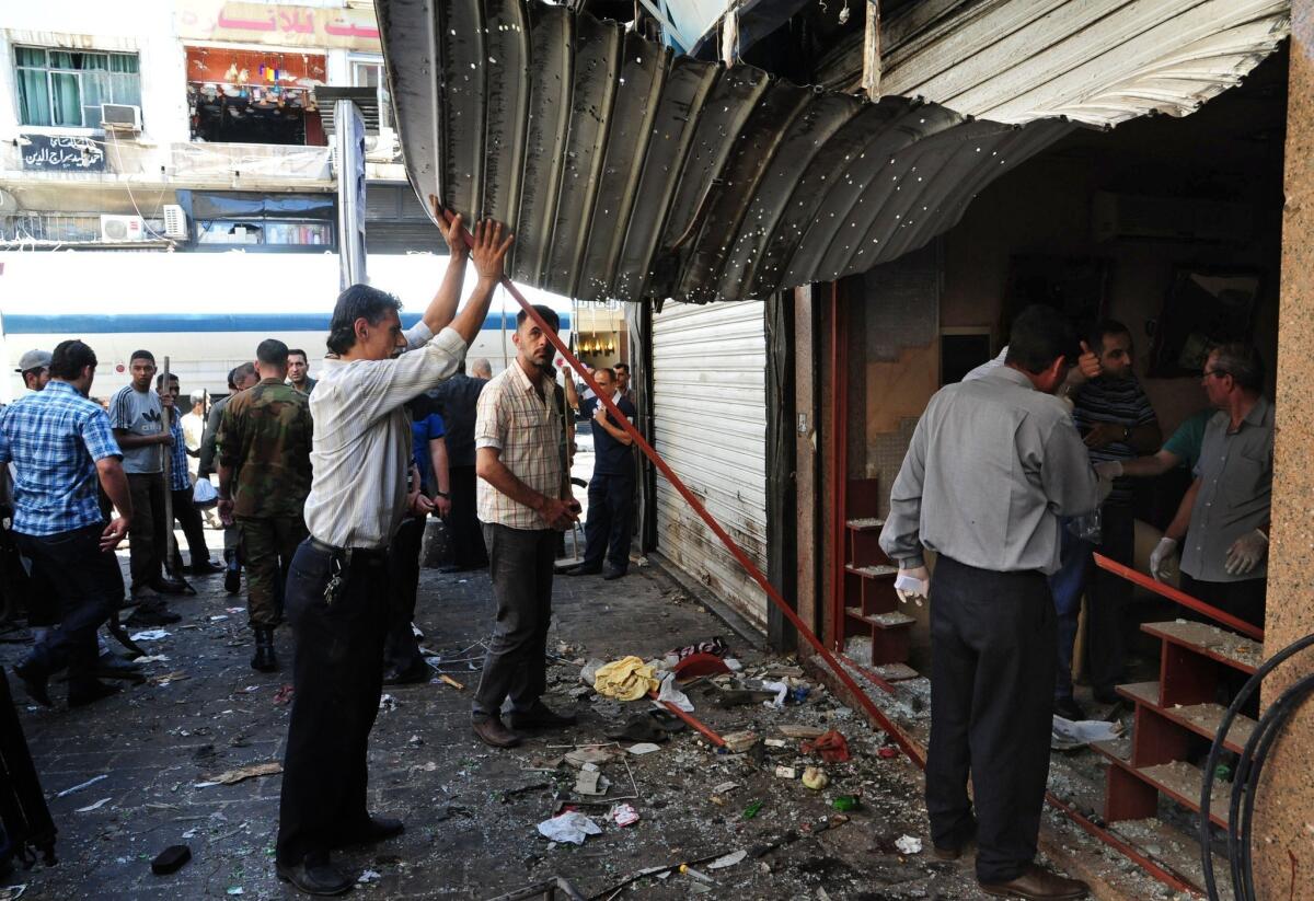 Men inspect a damaged shop at the scene of two explosions in Damascus, Syria.