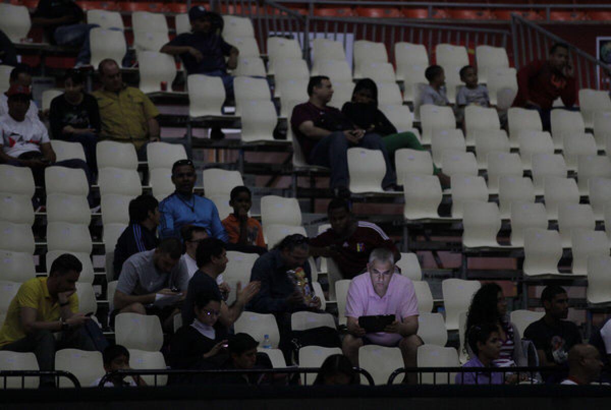 A fan looks at his laptop as he waits for play to resume at a World Cup qualifying basketball game during a power outage Tuesday in Caracas, Venezuela.