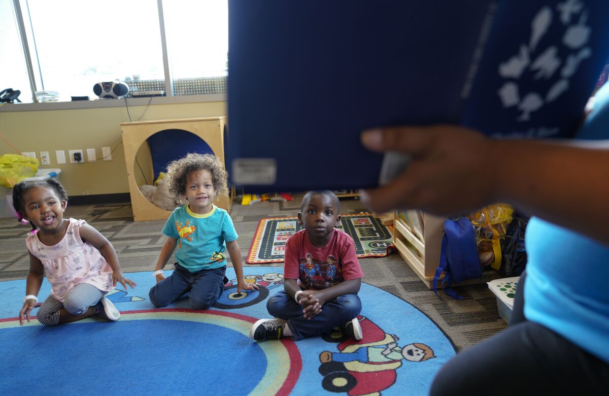 Una profesora de preescolar lee un libro de cuentos a los niños de preescolar 