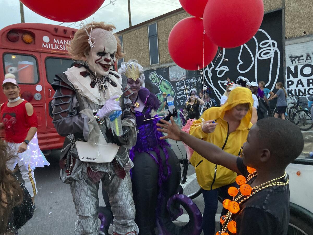 Un hombre disfrazado saluda a un niño en el desfile Krewe of Boo 