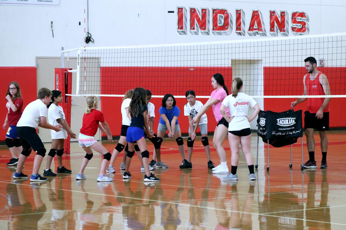 Real's Youth Volleyball Camp counselor Jolene Soliman shows participants how to receive the ball, at Burbank High School in Burbank on Thursday, July 28, 2019. The camp is set in two gyms, one for children ages 11-4 and the other for those 8-10.