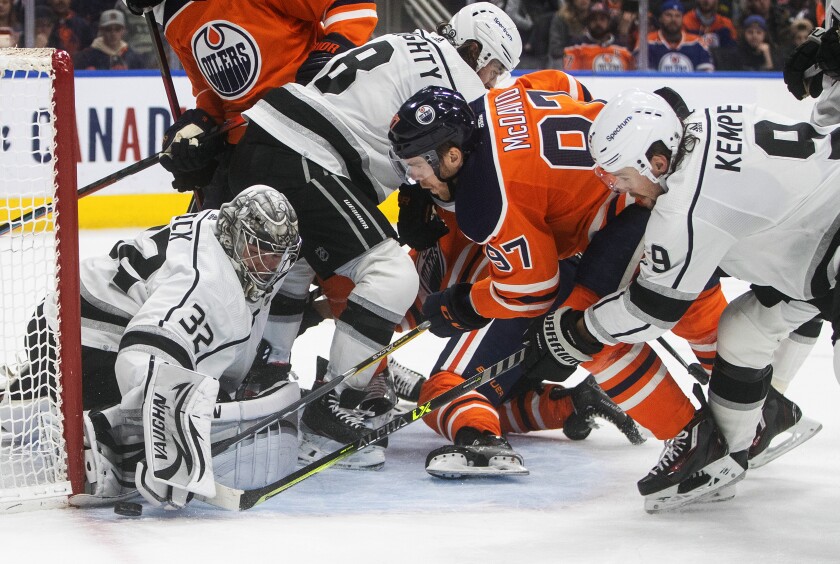 Kings goalie Jonathan Quick stops a shot by Edmonton Oilers forward Connor McDavid as Adrian Kempe defends.