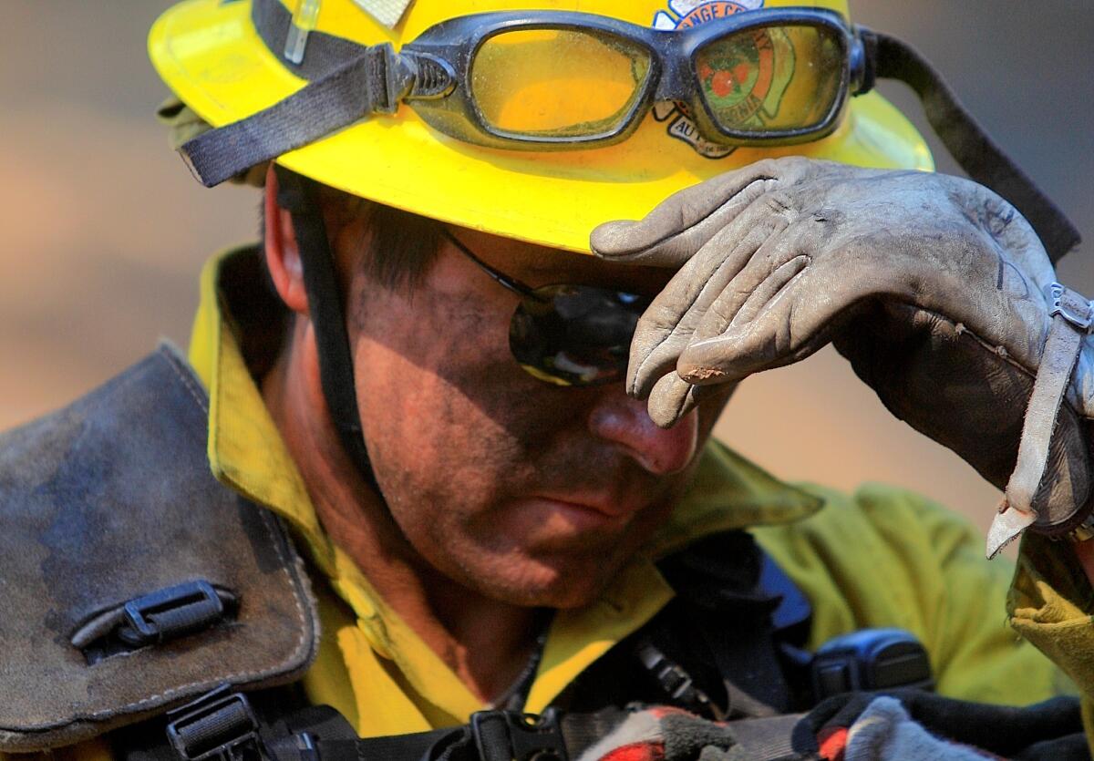 Orange County firefighter Duke Juarez takes a break after hiking up a steep hillside in high heat while extinguishing hot spots near homes in the Cleveland National Forest.