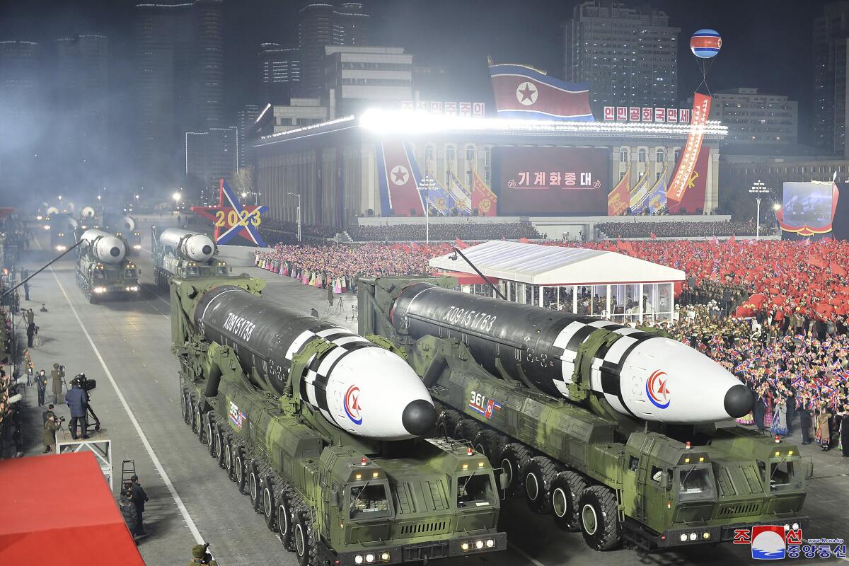 Missiles roll past crowds at a military parade.