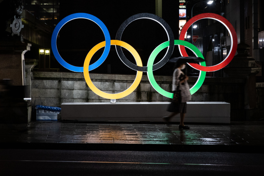 TOKYO, JAPAN - JULY 09: A woman wearing a face mask walks past the Olympic Rings on July 09, 2021 in Tokyo, Japan.