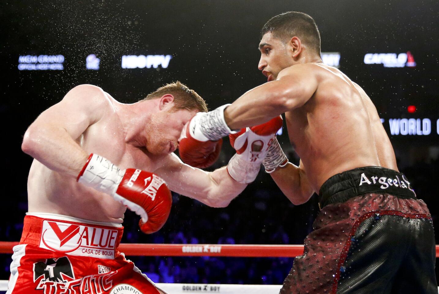 Canelo Alvarez, left, and Amir Khan trade punches inside during their WBC middleweight title fight Saturday.