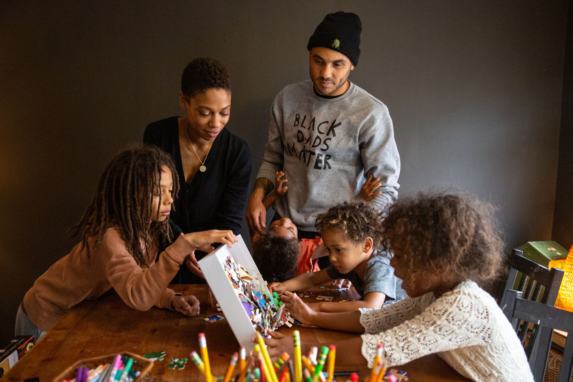 The Brown family gathers around their dining room table to work on a puzzle.