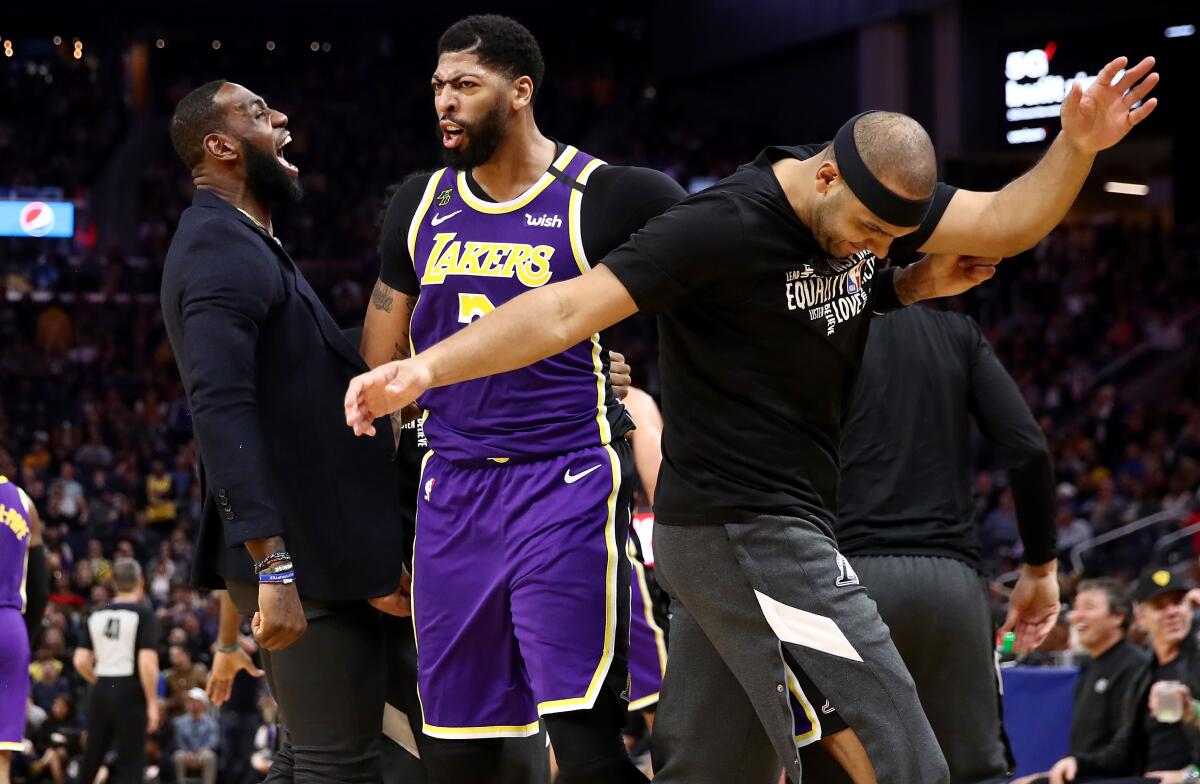 From left, LeBron James, Anthony Davis and Jared Dudley are pumped up in the Lakers' rout of the Warriors on Thursday night. With James sidelined, Davis had 23 points.