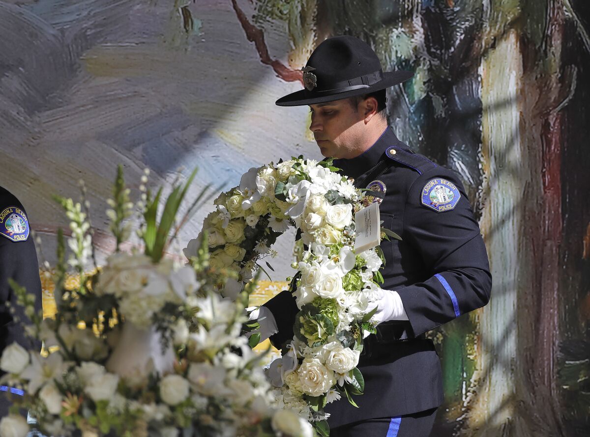 A Laguna Beach police officer carries a wreath to the stage.