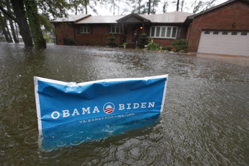 An Obama campaign sign rises above the floodwaters in front of a home as rain falls in Norfolk, Va.