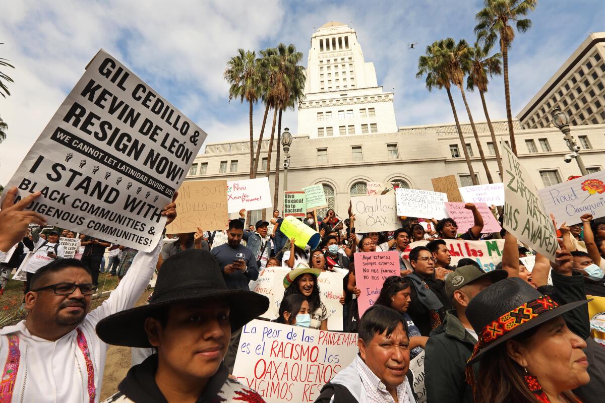 Protesters hold signs in front of City Hall.