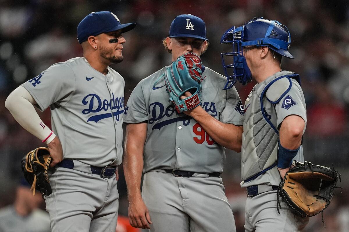 Dodgers pitcher Landon Knack speaks with catcher Will Smith and shortstop Miguel Rojas against the Braves.