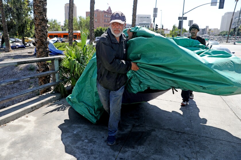 LOS ANGELES, CA - APRIL 12: Harvey Hernandez, 58, homeless for 22 years, moves his tent and belongings back to the sidewalk after the City of Los Angeles Sanitation Department powerwashed along Arcadia St. in downtown on Tuesday, April 12, 2022 in Los Angeles, CA. Section 41.18 of the Los Angeles Municipal Code (LAMC) makes it illegal to "sit, lie or sleep in or upon any street, sidewalk or other public way." (Gary Coronado / Los Angeles Times)