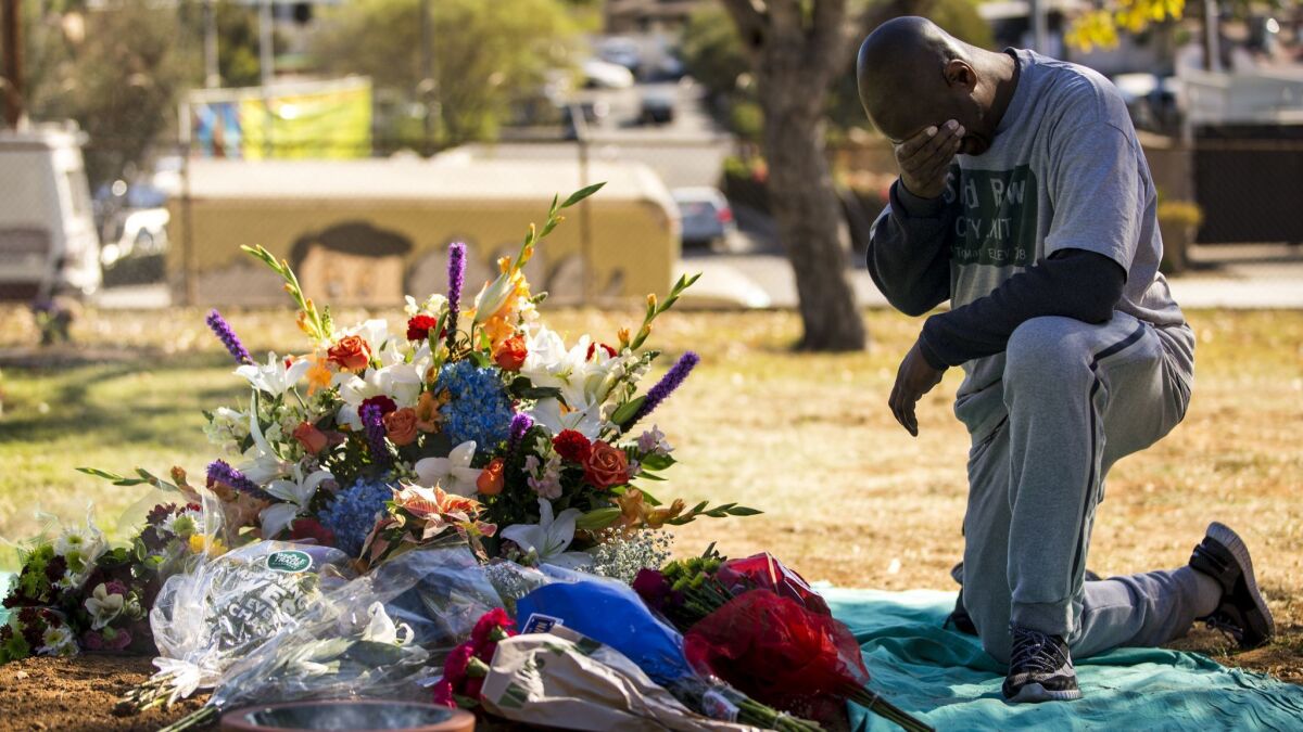 A man kneels by the site of a mass grave after an interfaith service for L.A. County's unclaimed dead in December 2017.