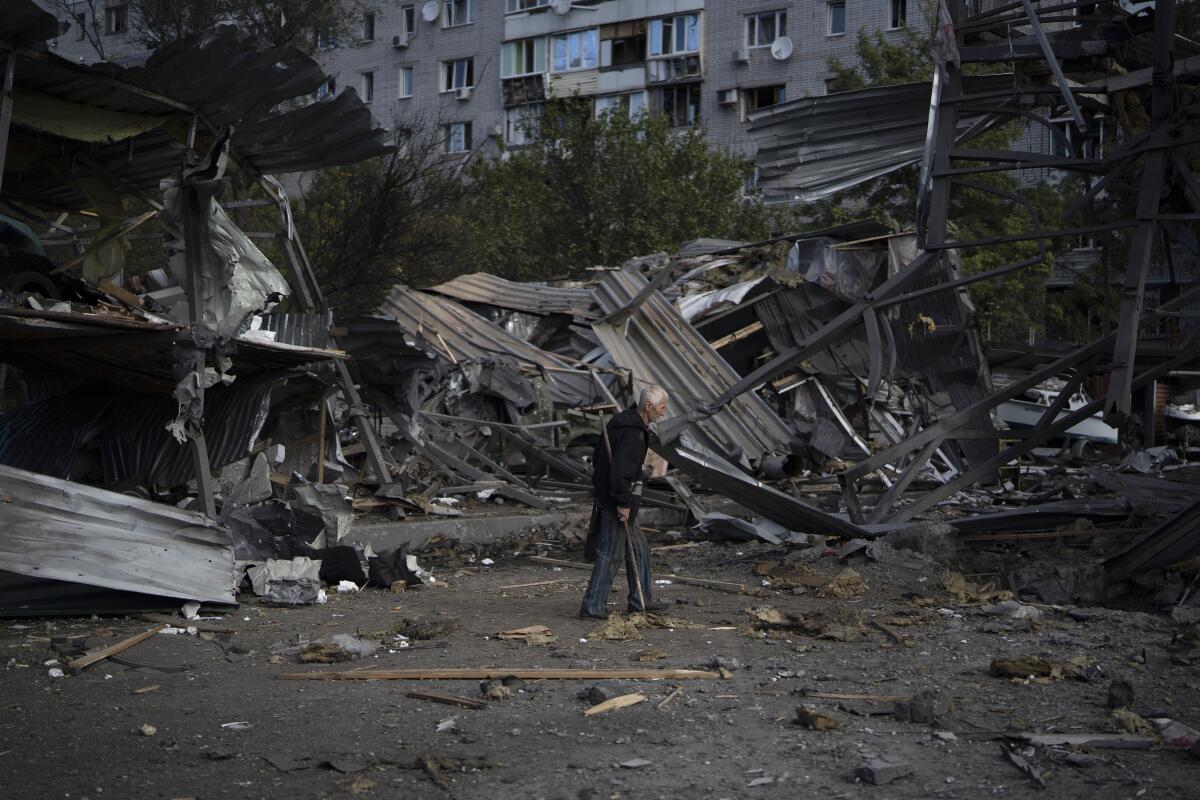 An elderly man walks past a car shop that was destroyed after a Russian attack in Zaporizhzhia, Ukraine, Tuesday