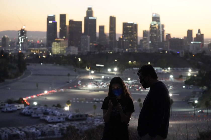 Visitors wear masks at a lookout point over at a COVID-19 vaccination site at Dodger Stadium Friday, Jan. 15, 2021, in Los Angeles. (AP Photo/Marcio Jose Sanchez)