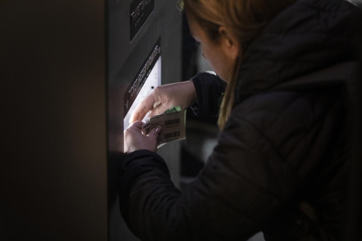A woman collecting her change from a ticket machine