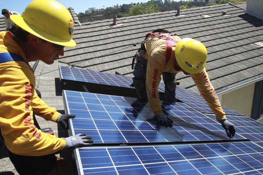Mike DeCarl and Christopher Johnson install solar panels on a home in Carlsbad in 2013