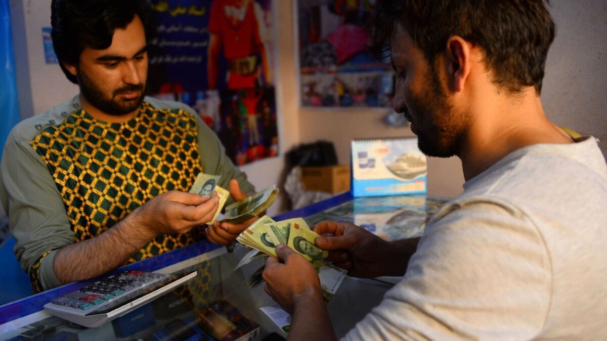 An Afghan returnee counts Iranian rials at a currency exchange in Herat province.