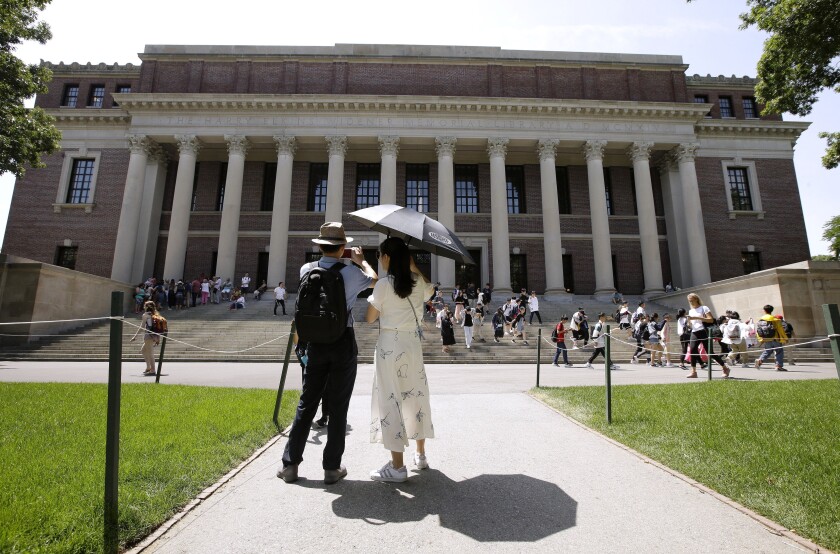 Tourists take pictures of Widener Library on the campus of Harvard University in Cambridge, Mass., in 2019.
