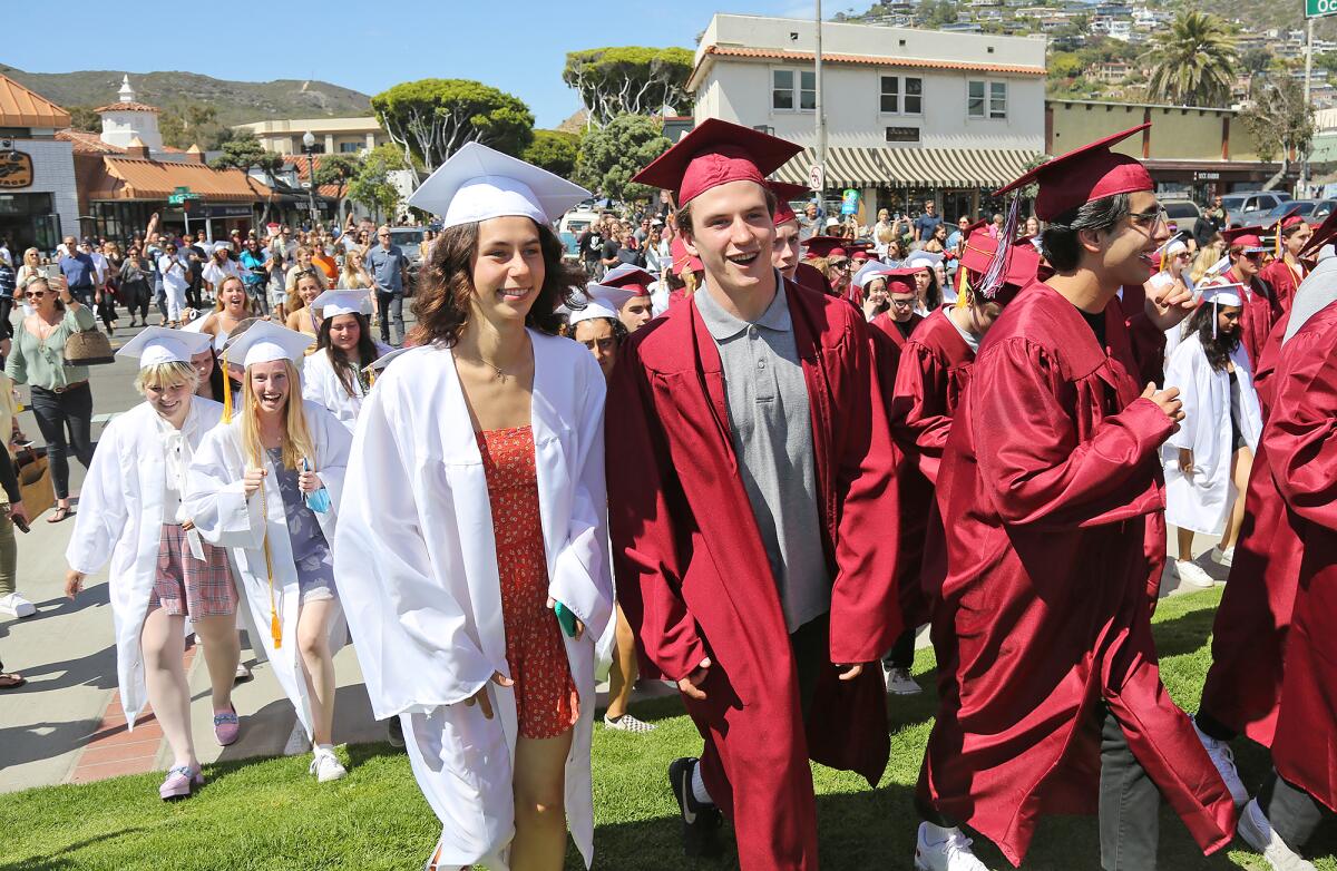 Graduates happily cross Coast Highway as they arrive on the grass during a Laguna Beach High class of 2021 graduation event.