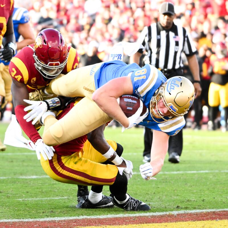 UCLA tight end Hudson Habermehl dives into the end zone past USC safety Anthony Beavers Jr. and defensive end Braylan Shelby.