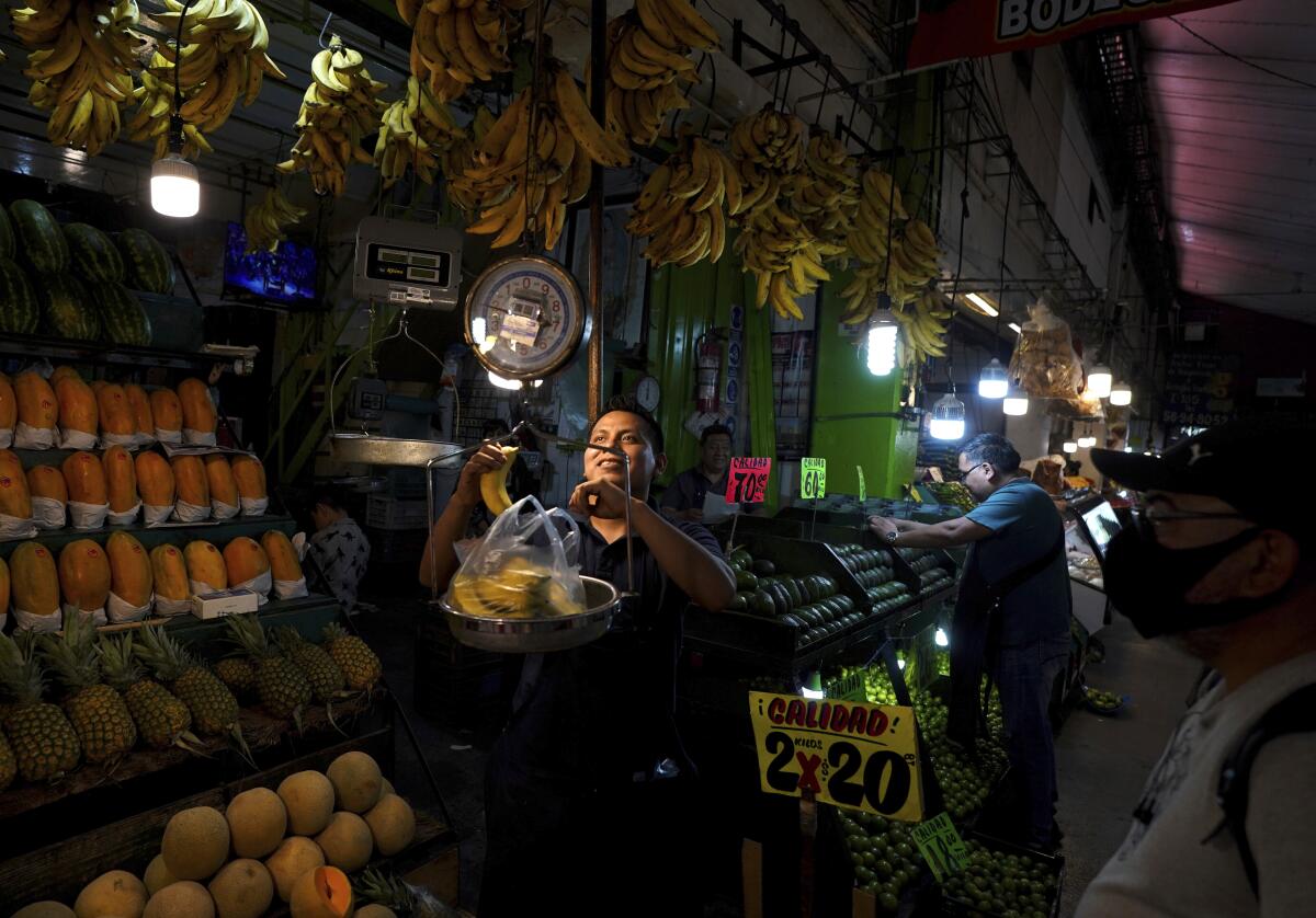 ARCHIVO - Una vendedora de frutas pesa plátanos en la Central de Abastos, 