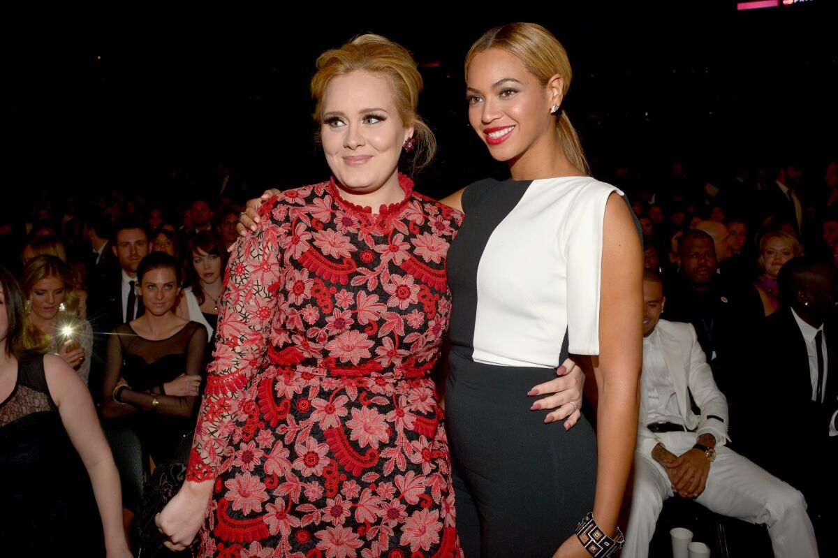 Two woman in formal attire pose for a photo with their arms around each other