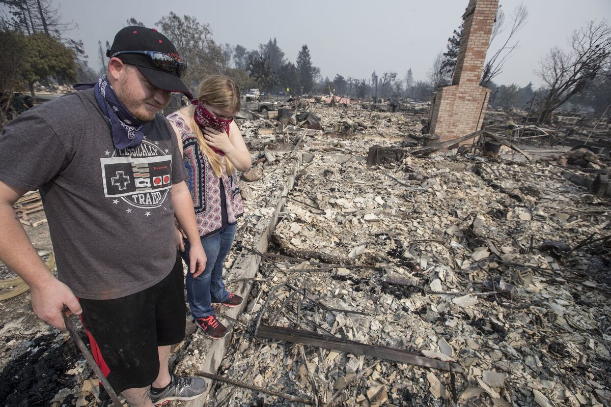 Spencer Blackwell, left, and Danielle Tate find Tate's father's gun collection, melted and burned, inside a gun safe at the ruins of her father's home in the Coffey Park neighborhood of Santa Rosa.