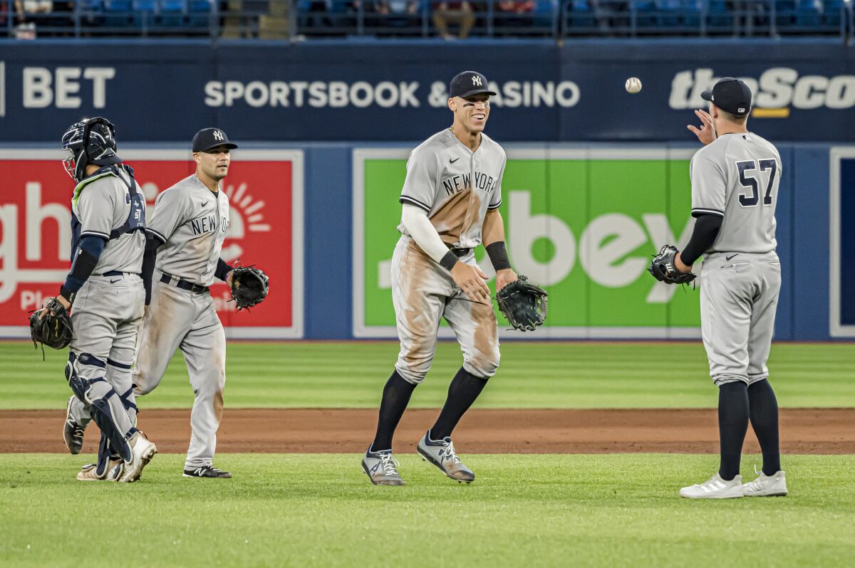 New York Yankees right fielder Aaron Judge, center, and relief pitcher Chad Green (57) celebrate after defeating the Toronto Blue Jays in nine innings of a baseball game in Toronto, Monday, May 2, 2022. (Christopher Katsarov/The Canadian Press via AP)
